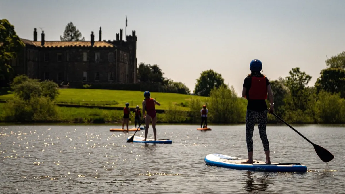 People paddleboarding on a lake near a large building.