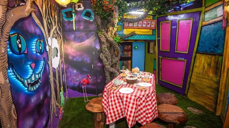 Whimsical room with Cheshire Cat mural and dining table.