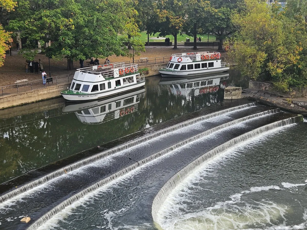 Two boats on a river near a small waterfall