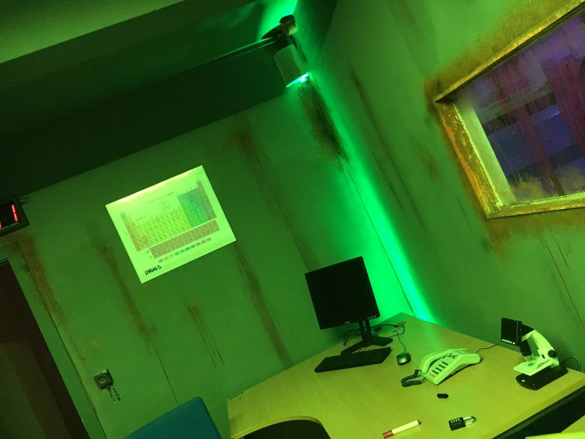 Dimly lit room with desk, computer, and microscope.