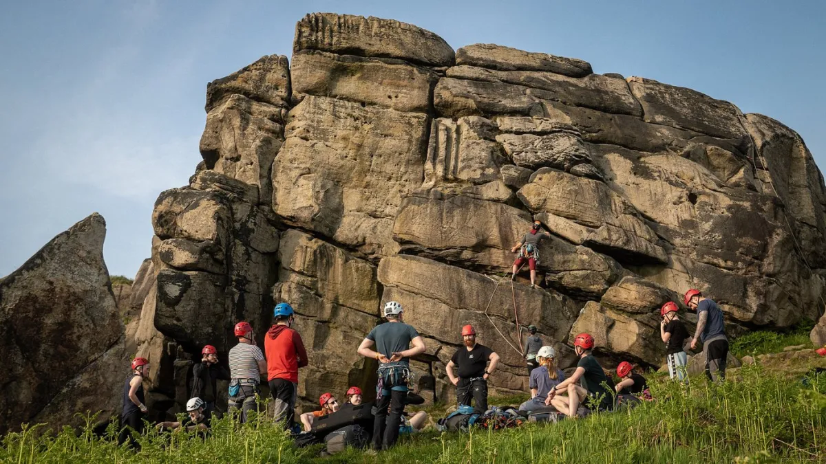 Group of people rock climbing with helmets.