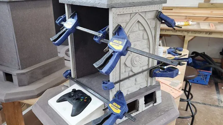 Stone structure clamped with tools, Xbox controller nearby.