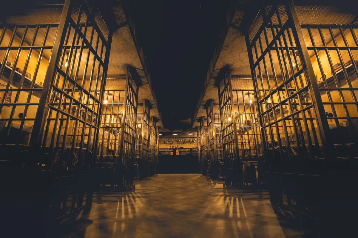 Dimly lit prison corridor with open cell doors