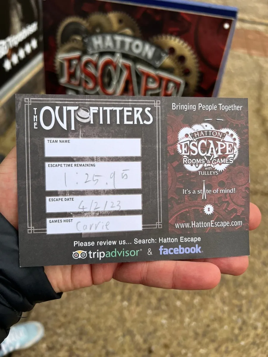 Hand holding an escape room card with details.