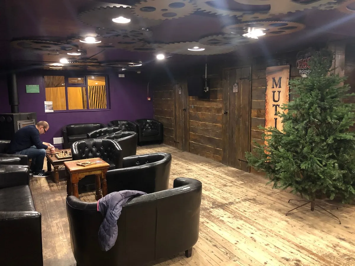 Man playing chess in a cozy lounge with leather chairs.