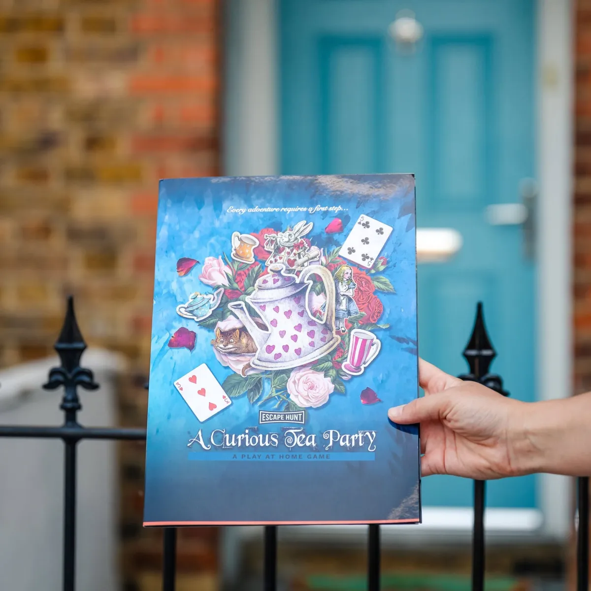 Hand holding a board game titled 'A Curious Tea Party'.