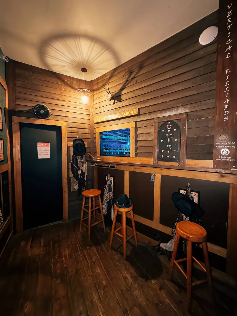 Interior of a rustic saloon with stools and hats.