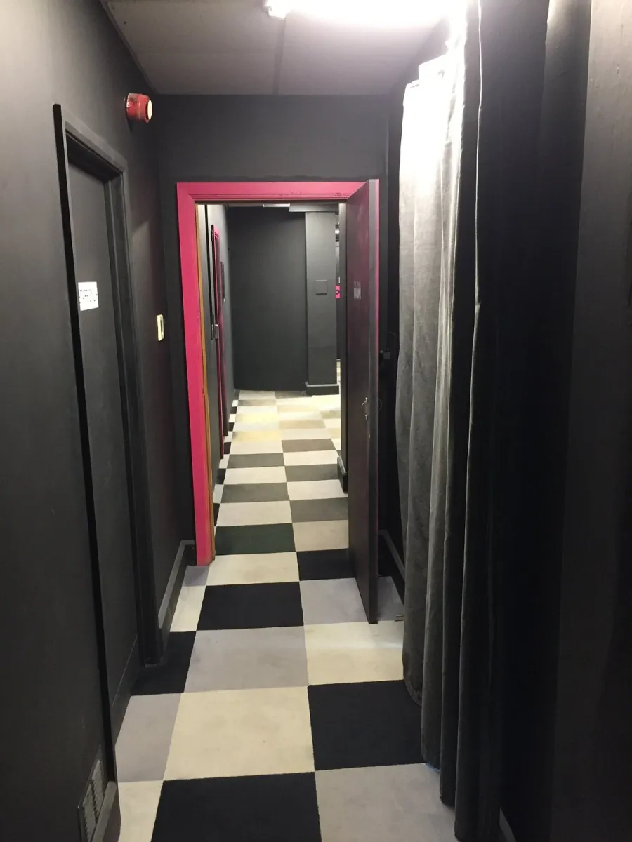 Narrow hallway with checkered floor and open door