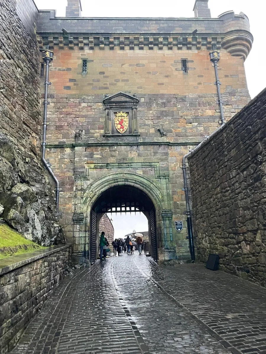 Stone castle gate with coat of arms above archway