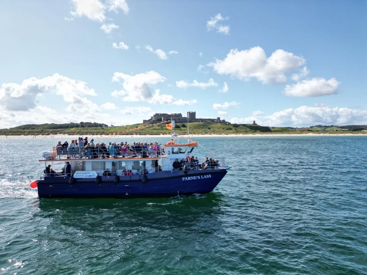 Tour boat on the water with a castle in the background.