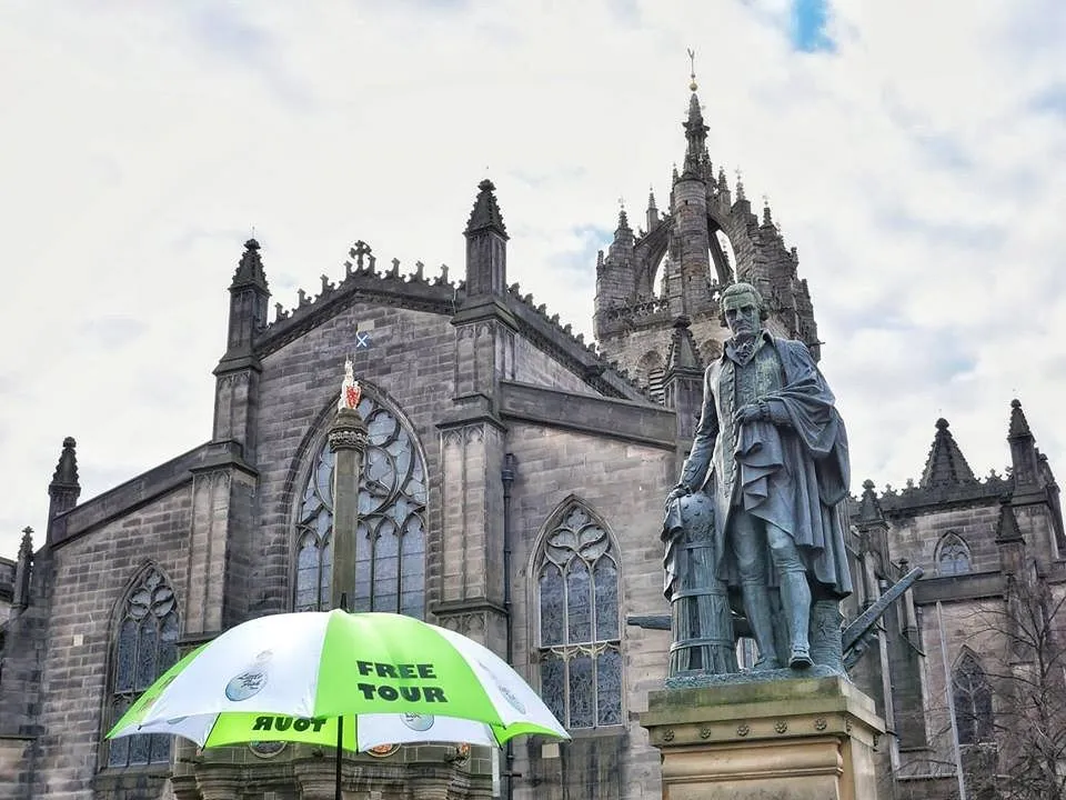 Statue in front of a historic church with a free tour umbrella.