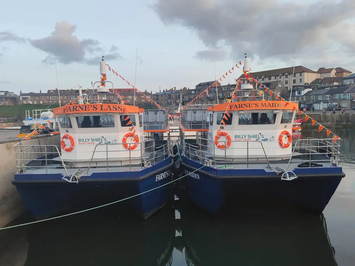 Two docked boats named Farne's Lass and Farne's Maiden.