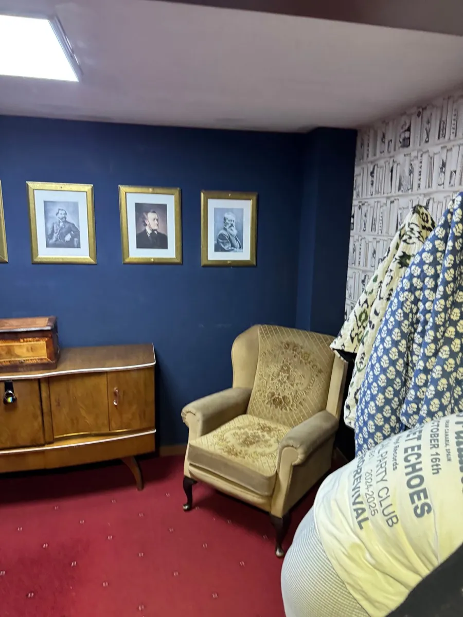 Room with vintage chair, cabinet, and framed portraits.