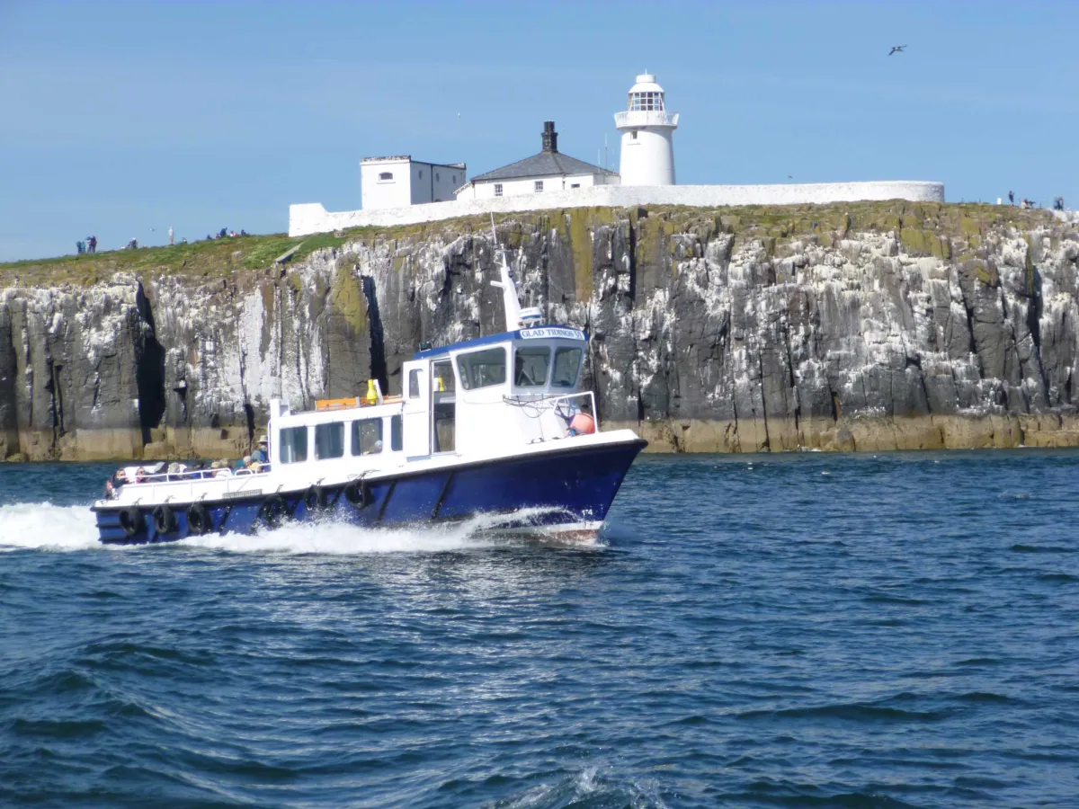 Boat sailing near a rocky island with a lighthouse