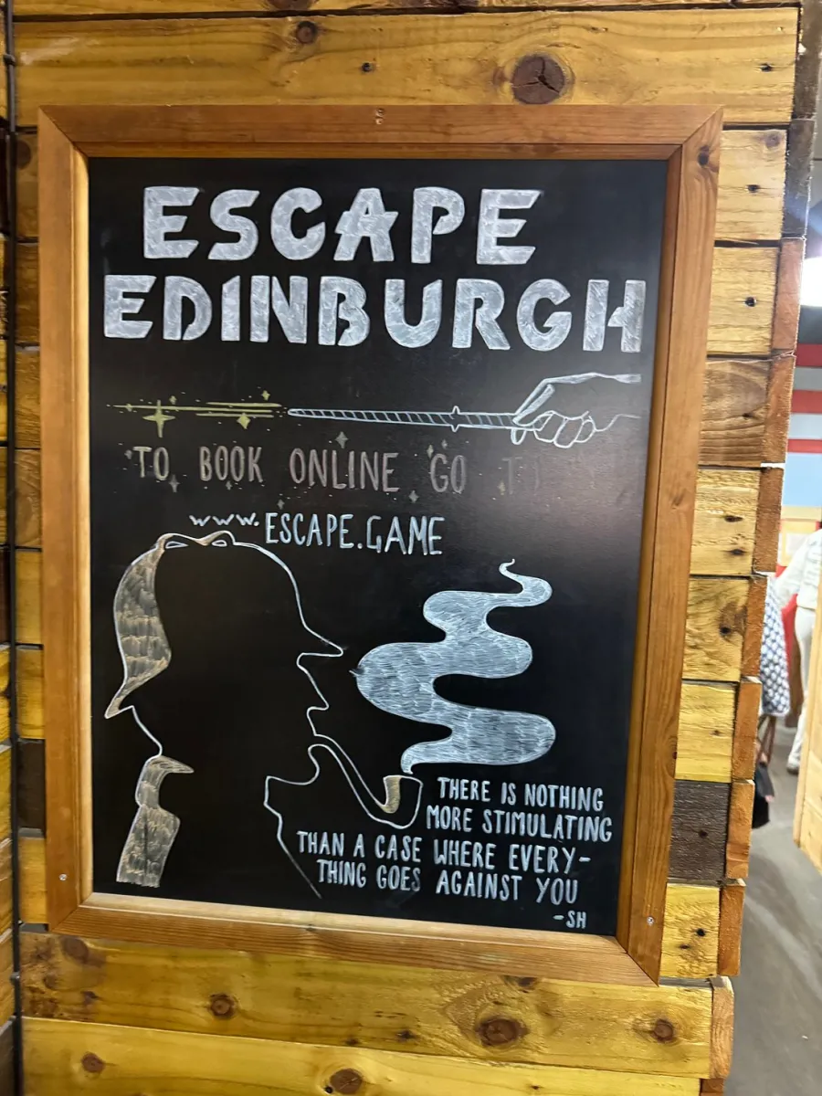 Chalkboard sign for Escape Edinburgh with detective silhouette.