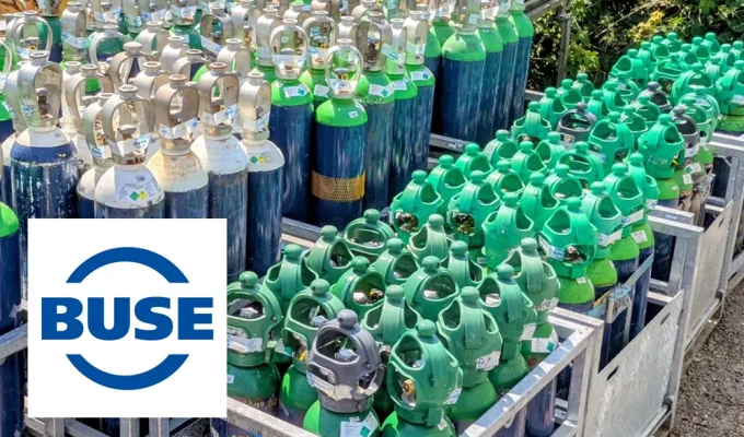 A selection of gas cylinders in storage, with a Buse Gas logo in the foreground